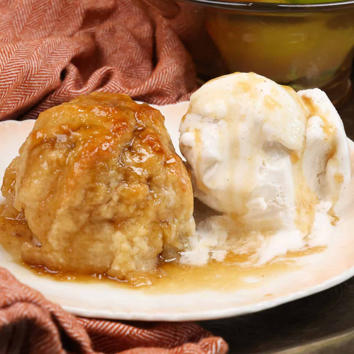 an apple dumpling with a scoop of ice cream on a plate topped with syrup.