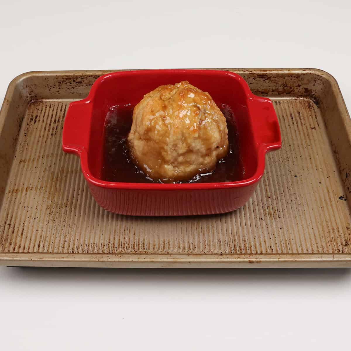 a single apple dumpling in a baking dish.