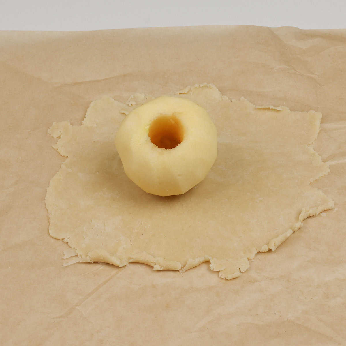 a cored apple in the center of a circle of pie crust.