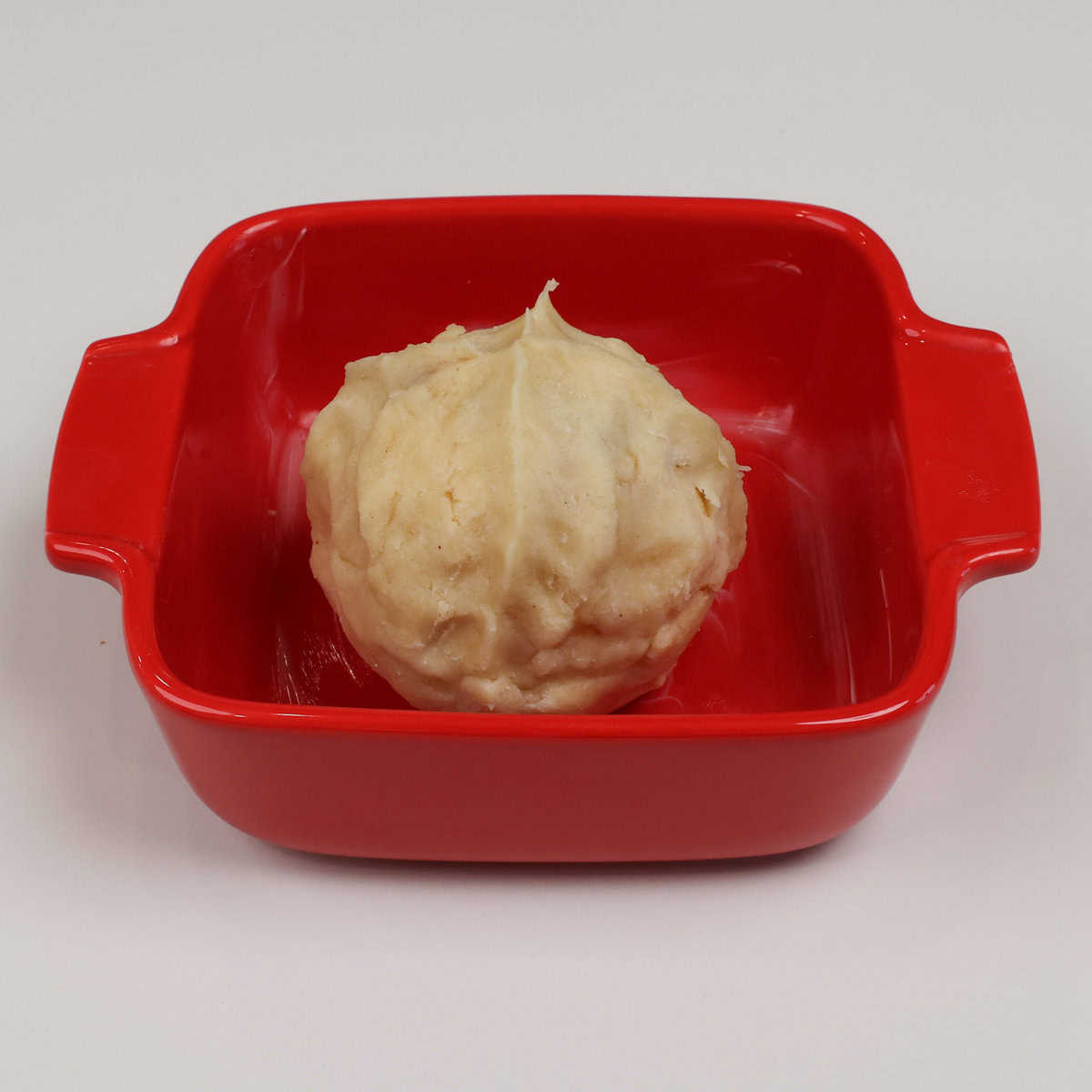 an unbaked apple dumpling in a baking dish.