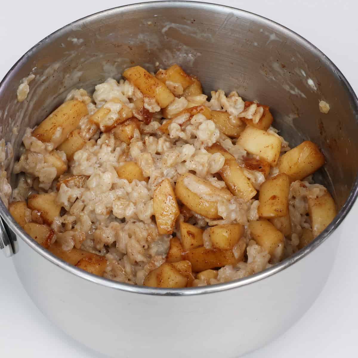 cooked oatmeal mixed with chopped apples and brown sugar in a pot.