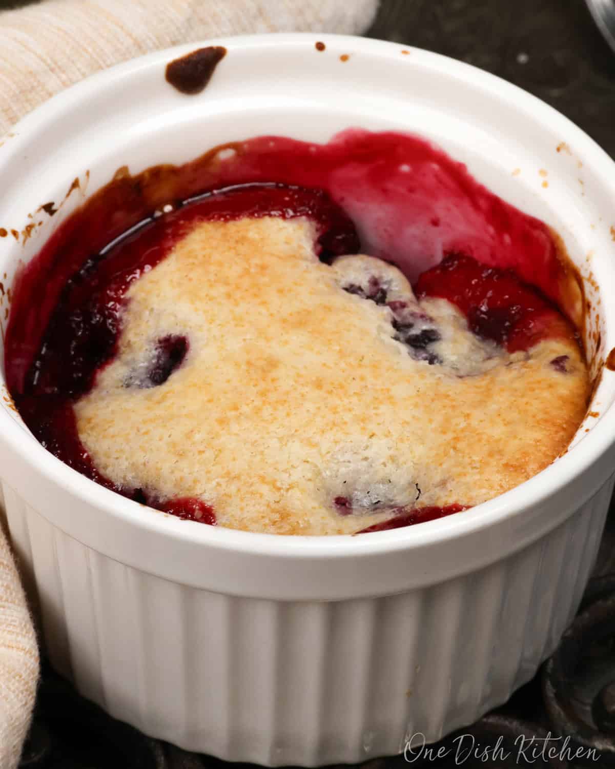 a single serving blackberry cobbler in a white ramekin.
