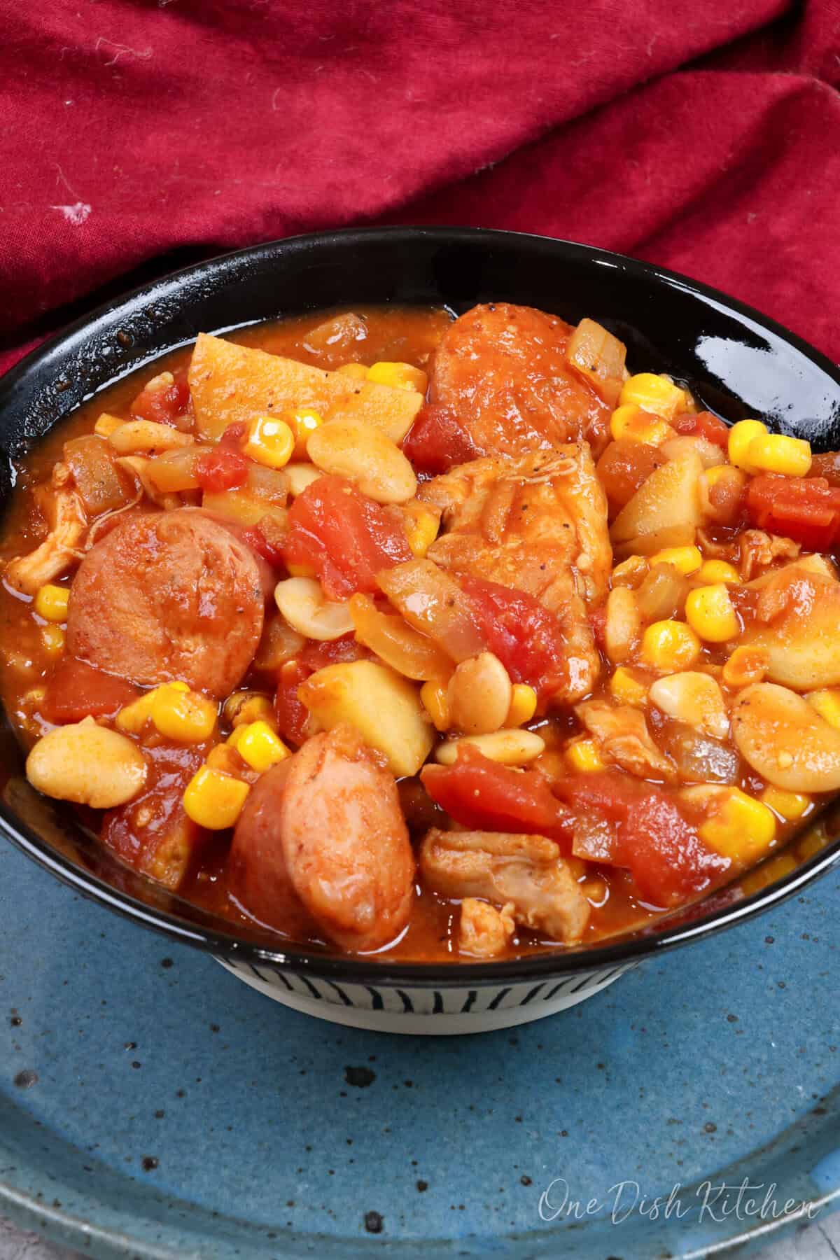 a bowl of brunswick stew next to a red napkin.