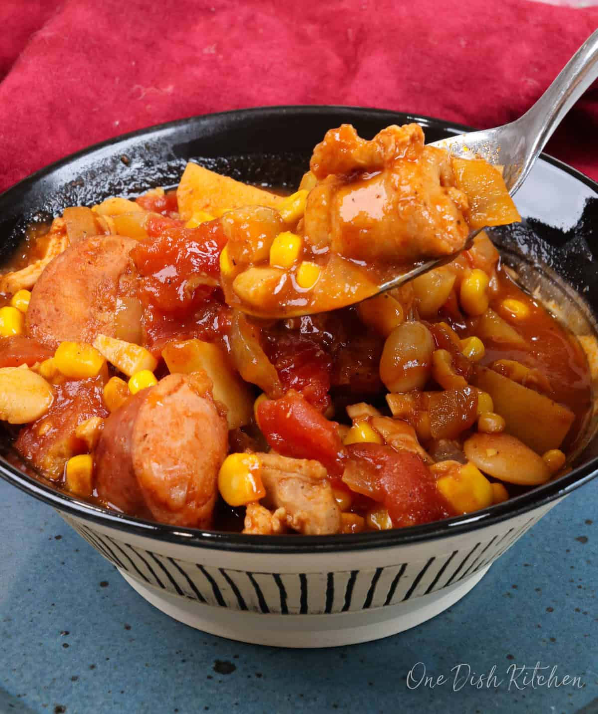 a spoonful of chicken and sausage from brunswick stew over the bowl of stew.