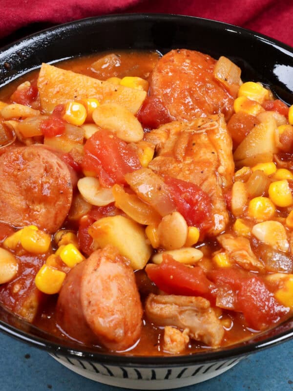 a bowl of brunswick stew next to a red napkin.