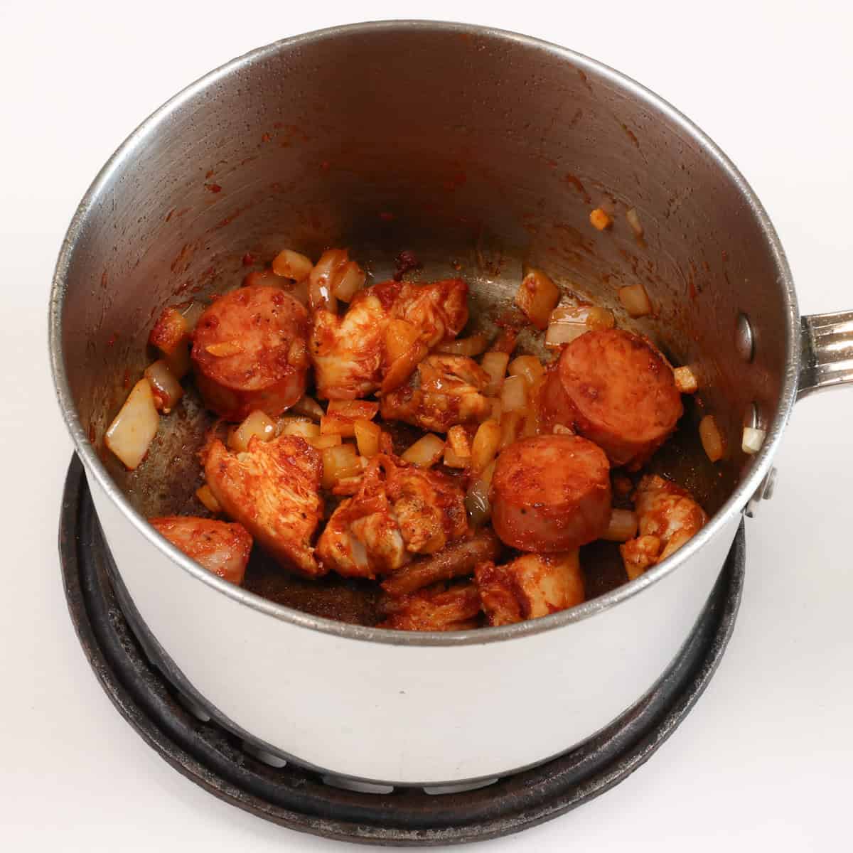 tomato paste, sausage, chicken and vegetables in a small pot.