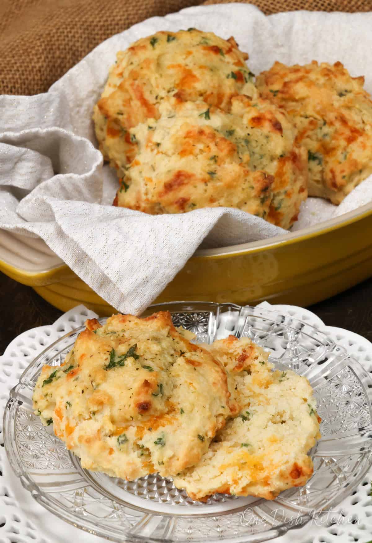 a bowl filled with three cheese biscuits and one biscuit on a white plate.