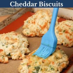 brushing butter over cheese biscuits on a baking sheet.