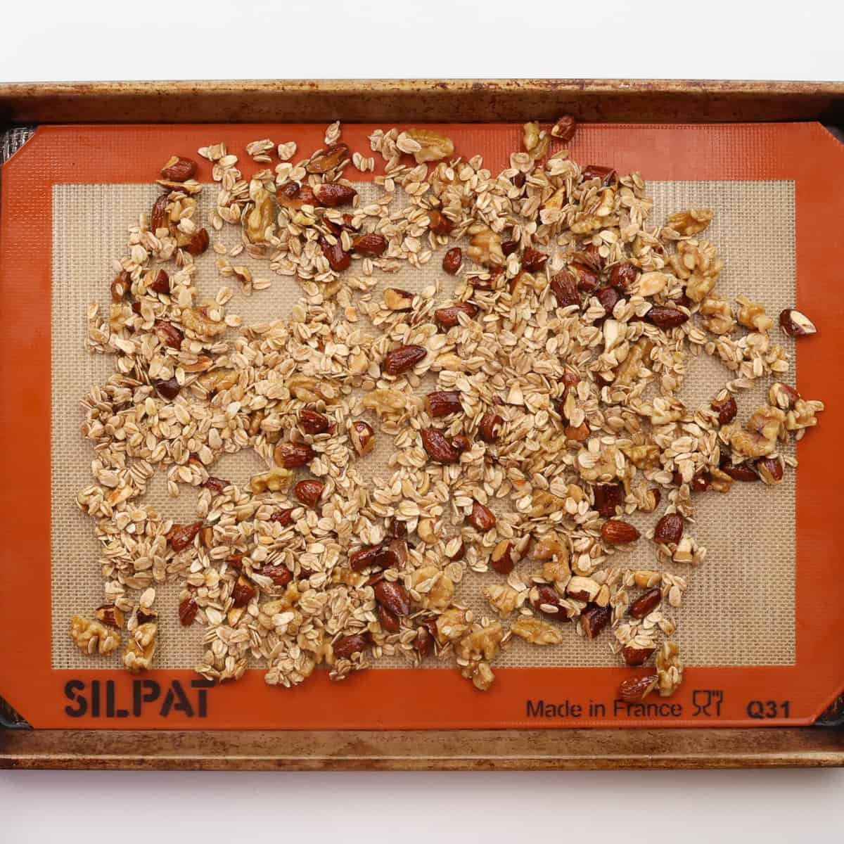 unbaked granola spread out on a baking sheet.