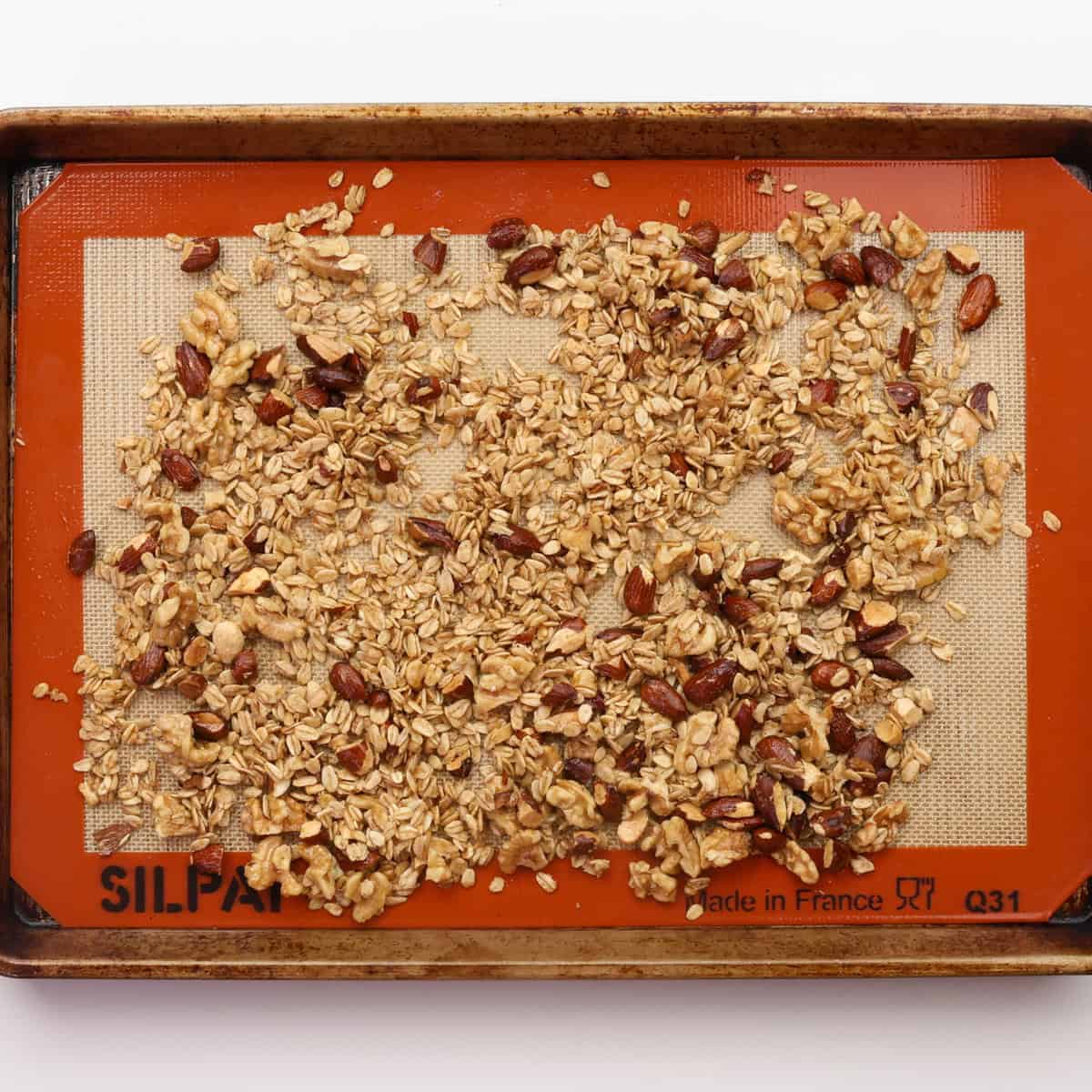 granola on a baking sheet after 10 minutes of baking.