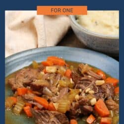 cooked chuck roast on a plate with gravy and carrots.