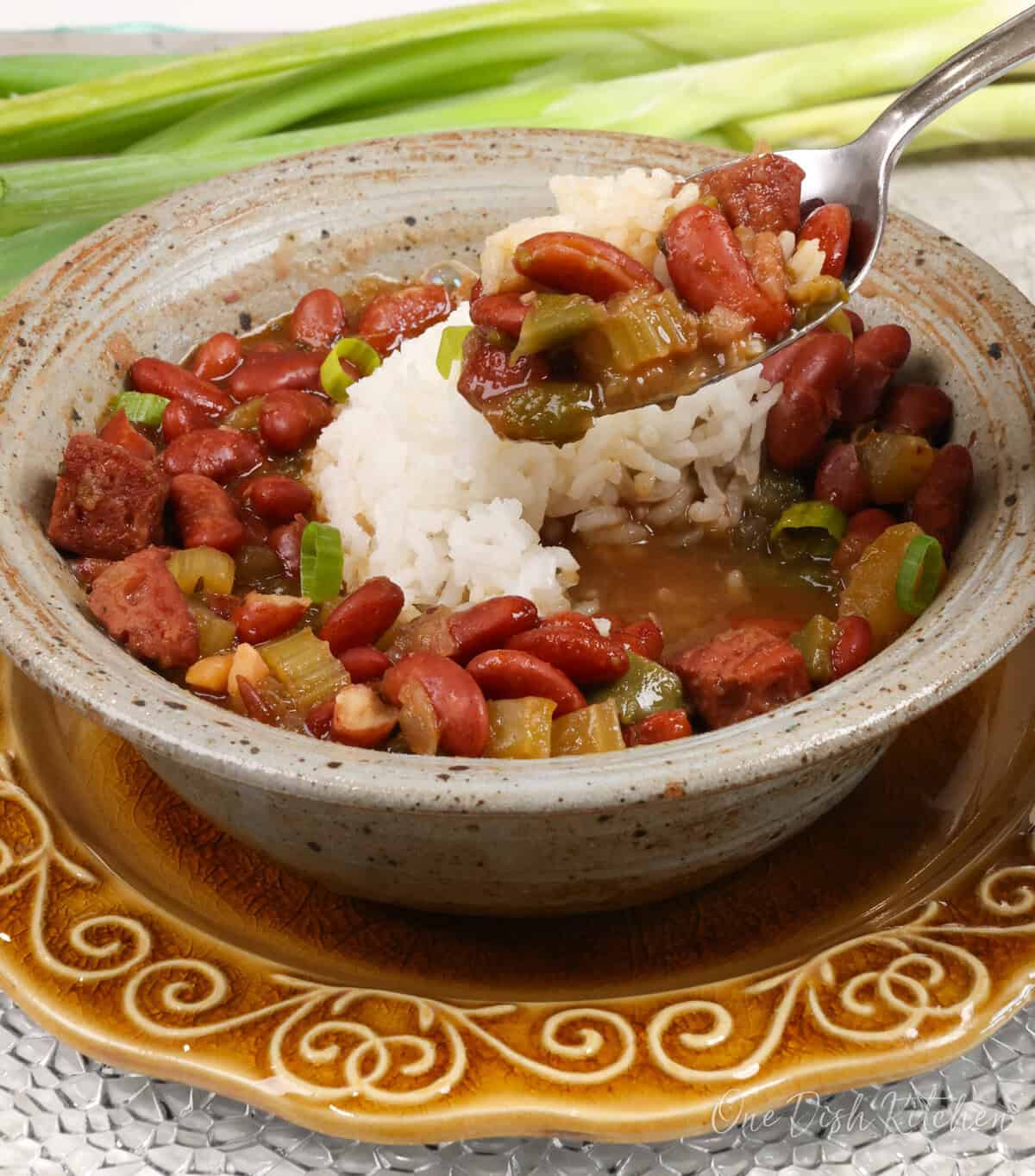 a bowl of red beans and rice with a spoon on the side.