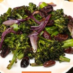 charred broccolini on a plate with red onions and kalamata olives.