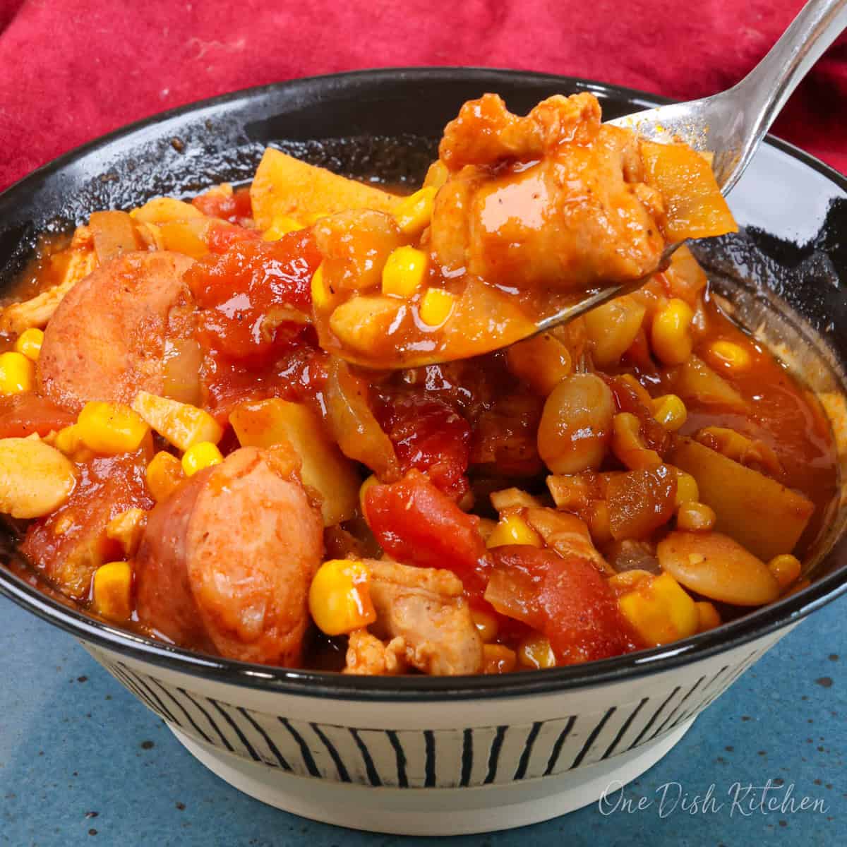 a small bowl of brunswick stew with a spoon on the side.