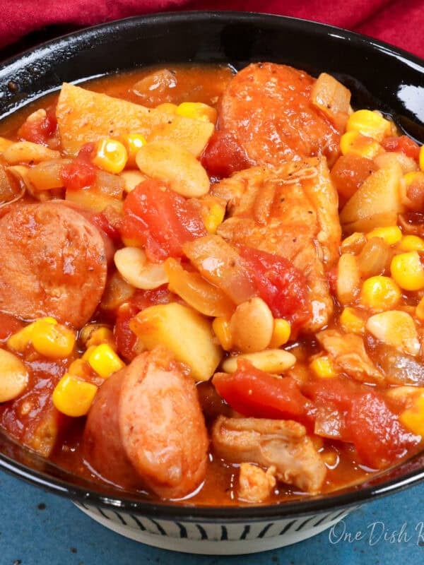 a bowl of brunswick stew next to a red napkin.