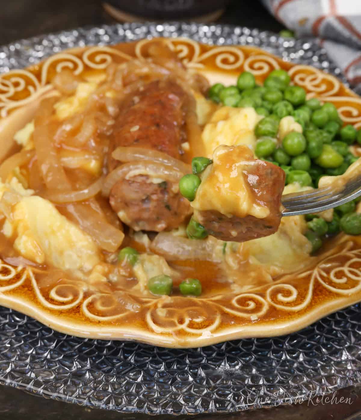 bangers and mash on a plate with a fork on the side.