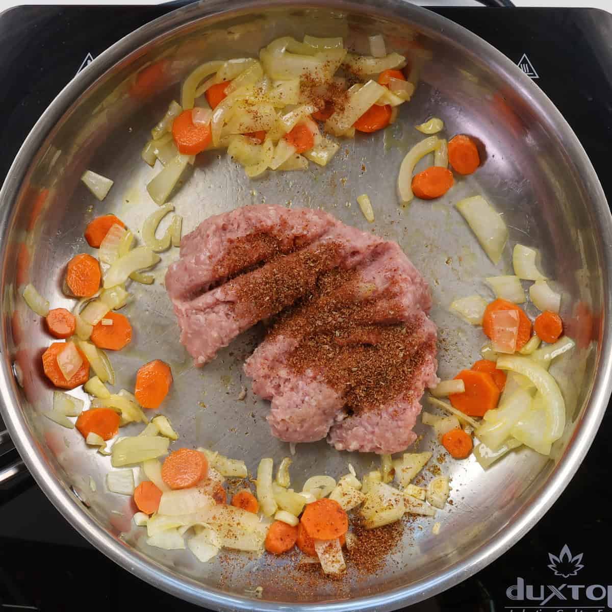 sauteed vegetables with ground turkey and taco seasoning in a skillet.