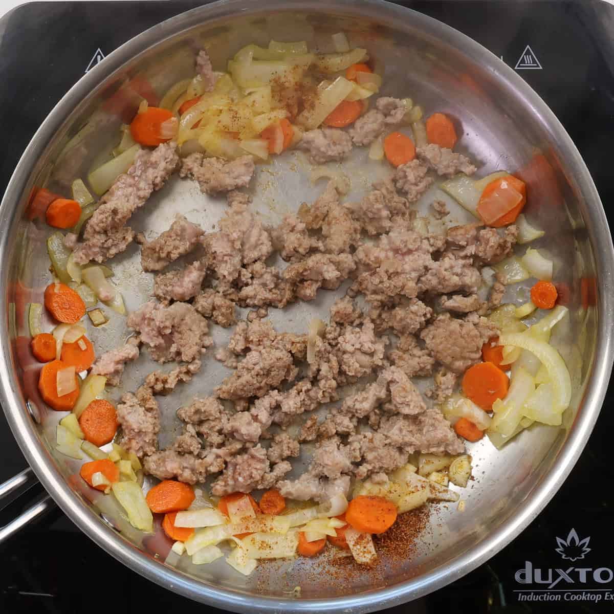 cooked ground turkey in a pan surrounded by carrots and onions.