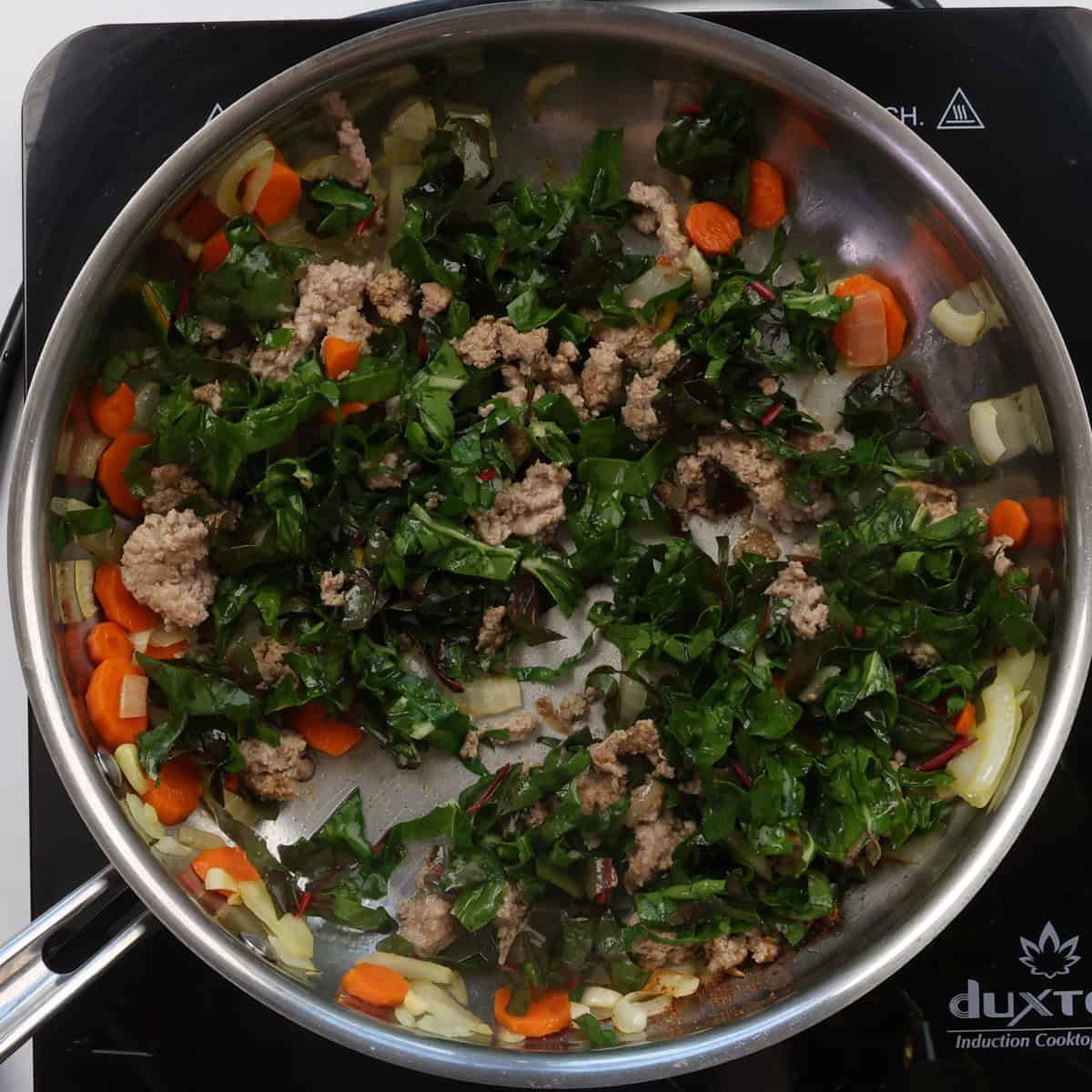 cooked ground turkey and vegetables along with swiss chard in a skillet.