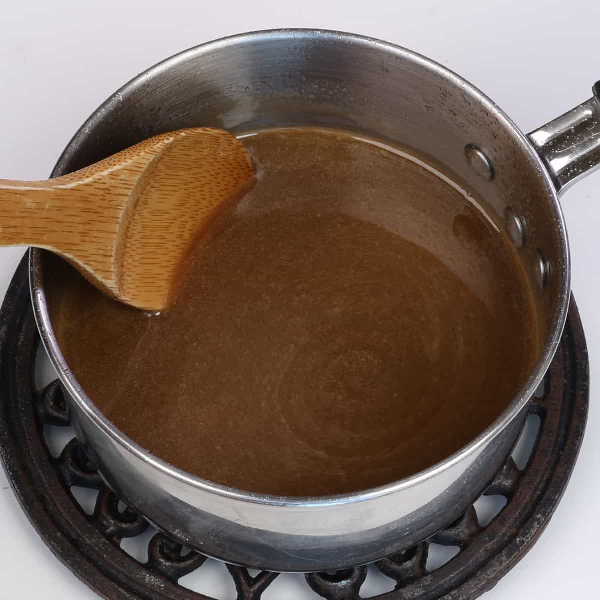 homemade pancake syrup in a pot with a wooden spoon on the side.