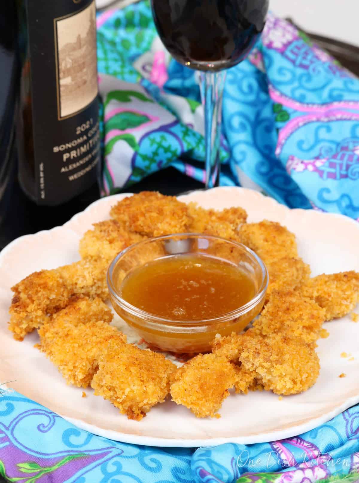 popcorn chicken on a white plate with a bowl of sauce in the center.