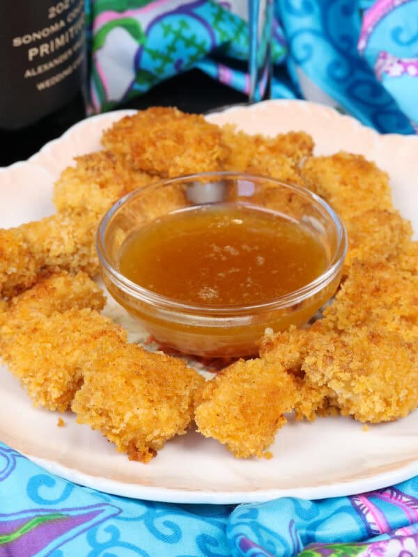 popcorn chicken on a white plate with a bowl of sauce in the center.