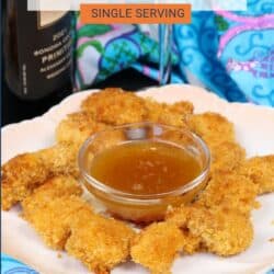 popcorn chicken on a white plate with a bowl of sauce in the center.