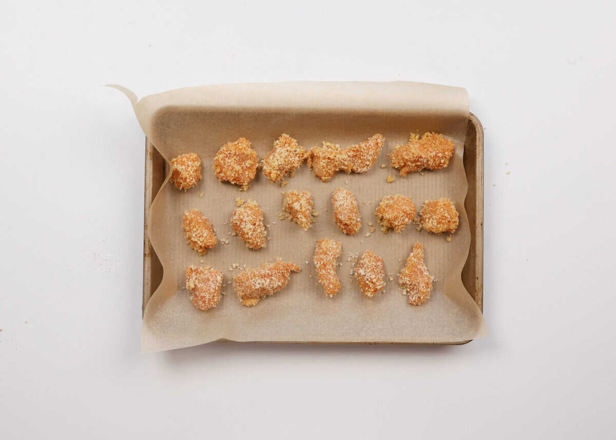 unbaked popcorn chicken on a baking sheet.