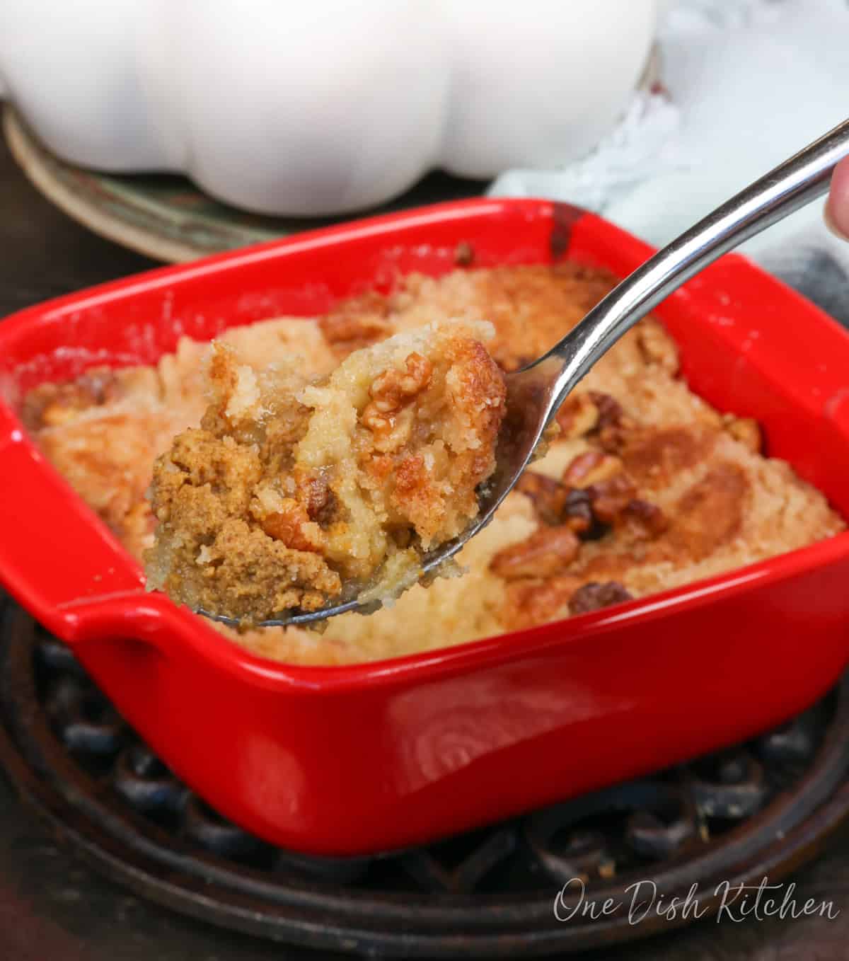 a small pumpkin dump cake in a square red baking dish with a spoon on the side.