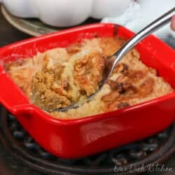 a small pumpkin dump cake in a square red baking dish with a spoon on the side.