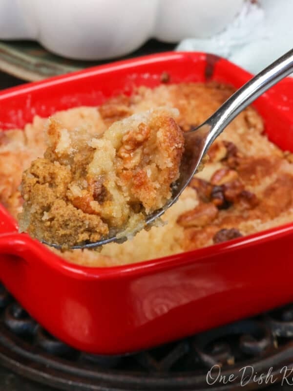 a small pumpkin dump cake in a square red baking dish with a spoon on the side.