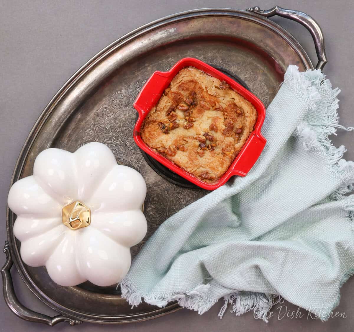 a pumpkin dump cake on a silver tray next to a white pumpkin and a blue napkin.