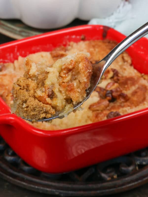 a small pumpkin dump cake in a square red baking dish with a spoon on the side.