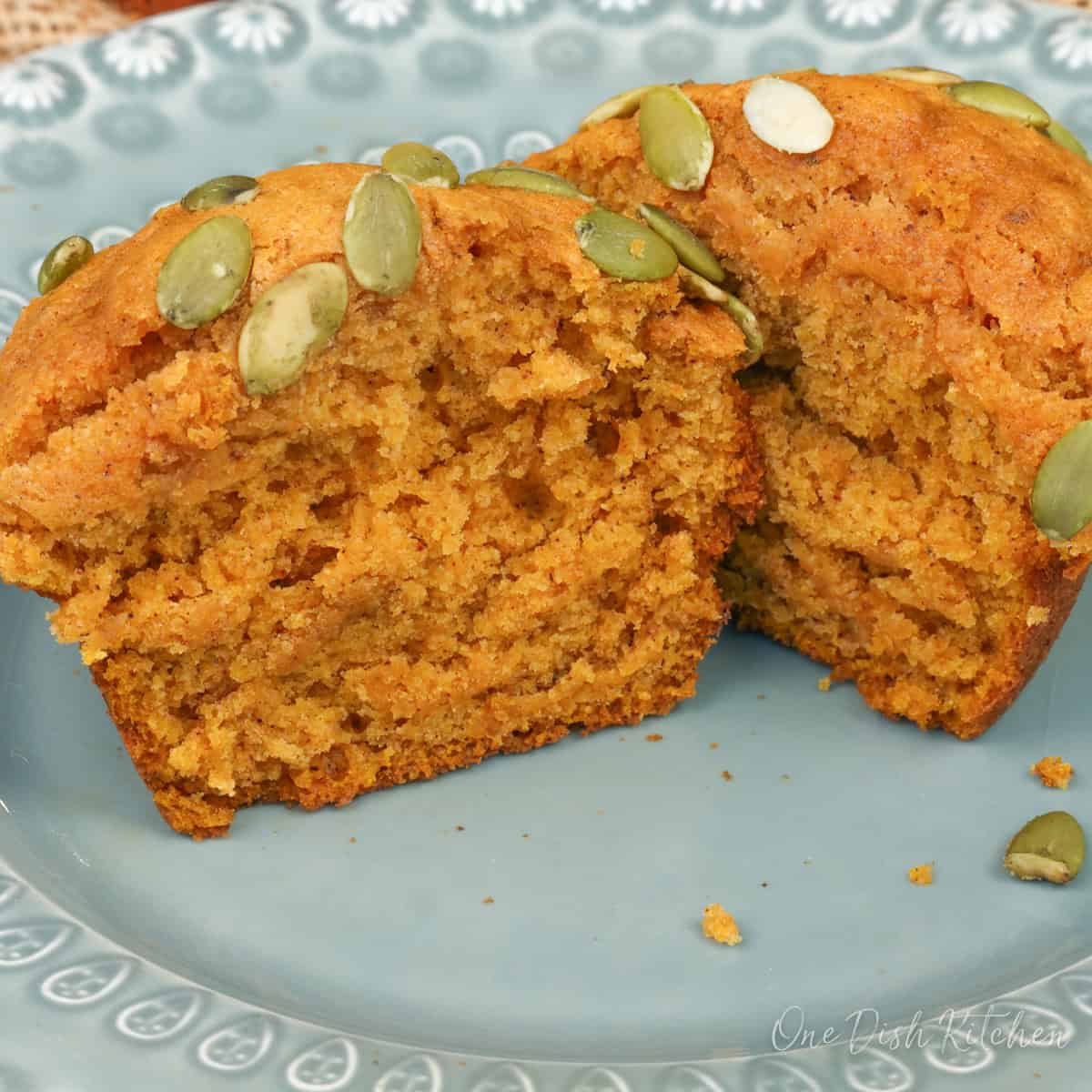 one pumpkin spice muffin sliced in half on a green plate.