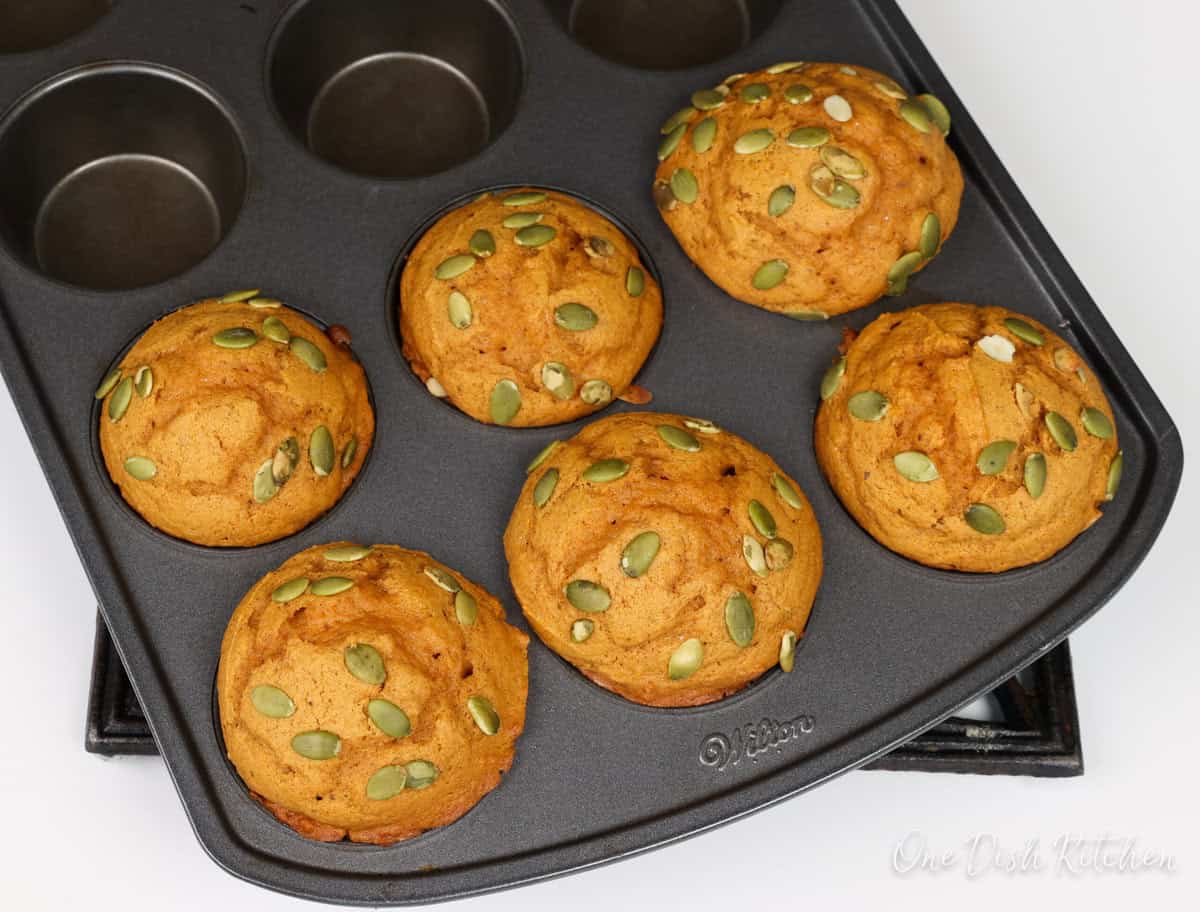 six pumpkin spice muffins in a muffin pan.