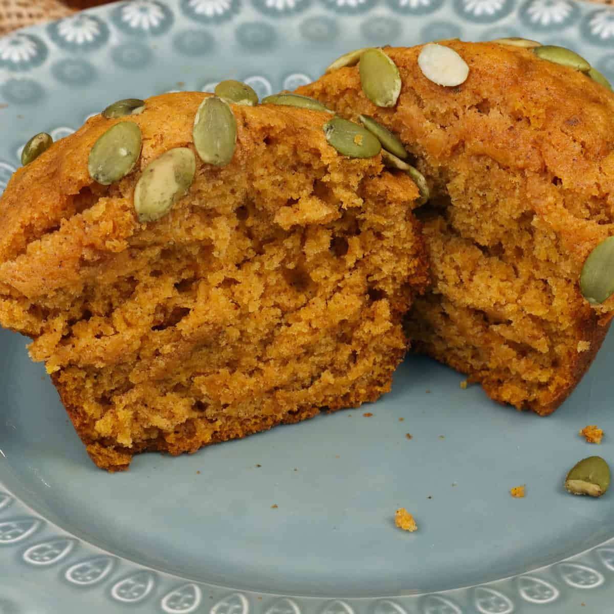 one pumpkin spice muffin sliced in half on a green plate.