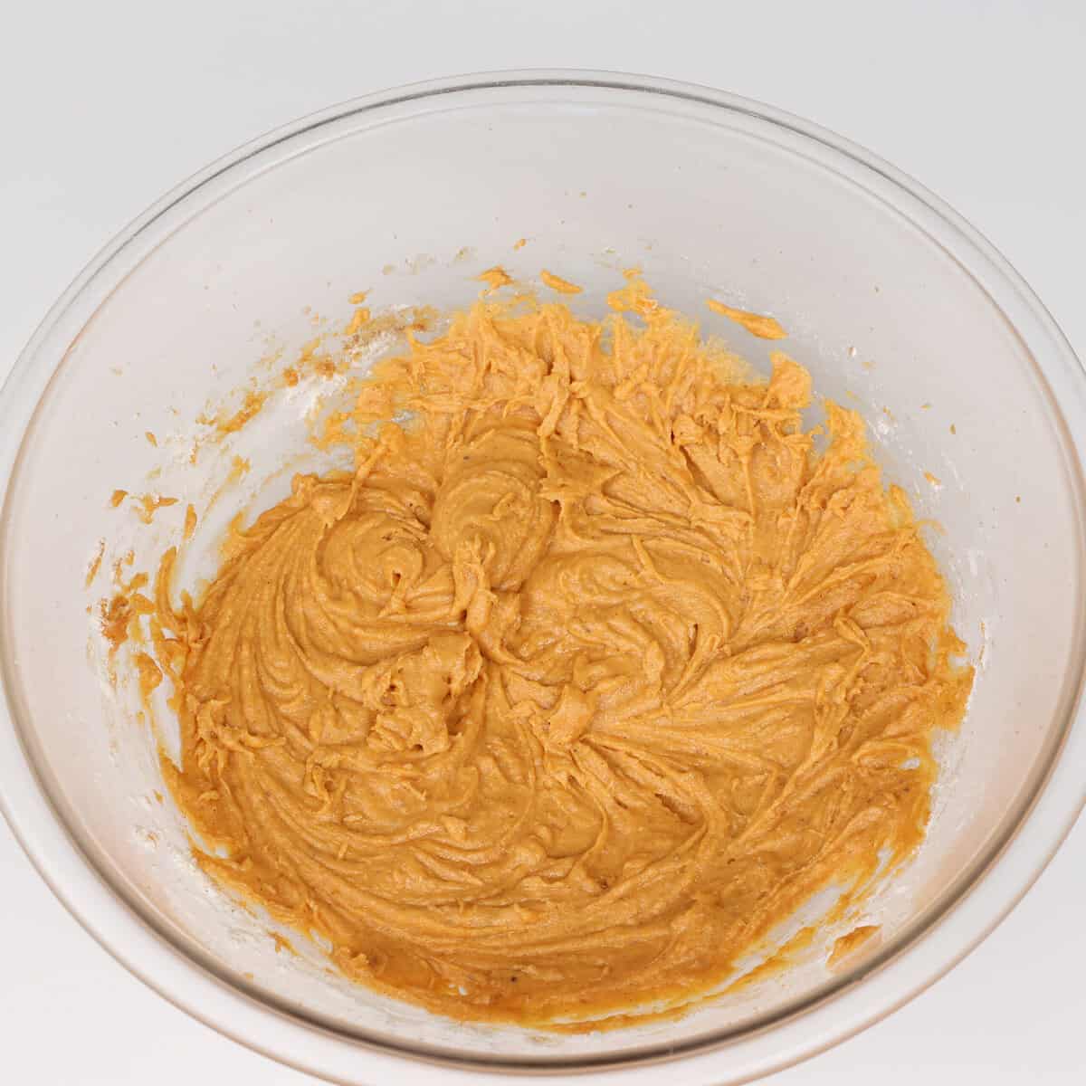 flour added to a mixing bowl along with pumpkin puree, sugars, and egg, and butter.