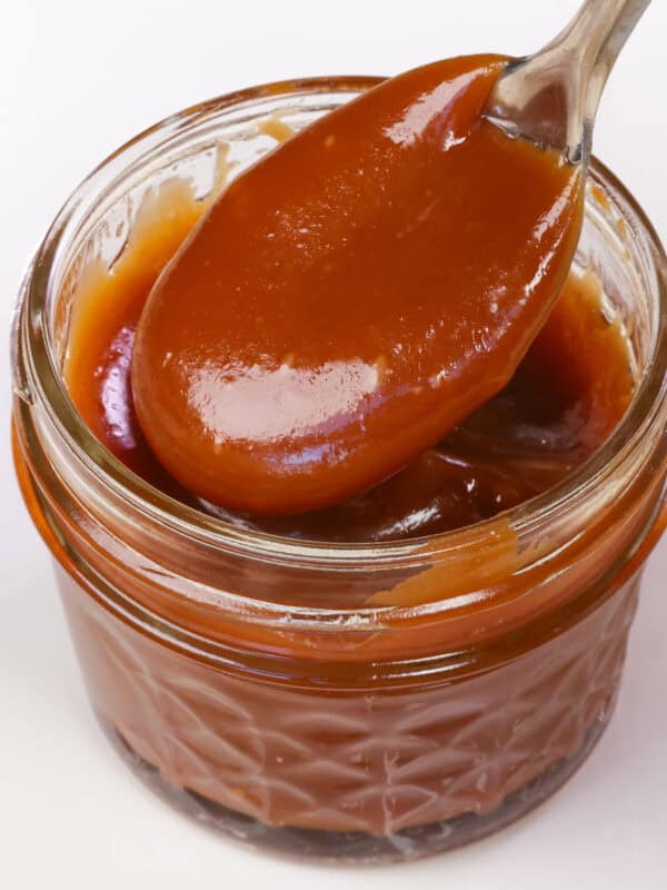 a small jar of caramel with a spoon on the side.