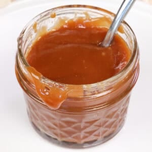 a small jar of caramel with a spoon on this side.