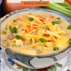 a bowl of cheeseburger soup topped with fresh shredded cheese and sliced green onions.