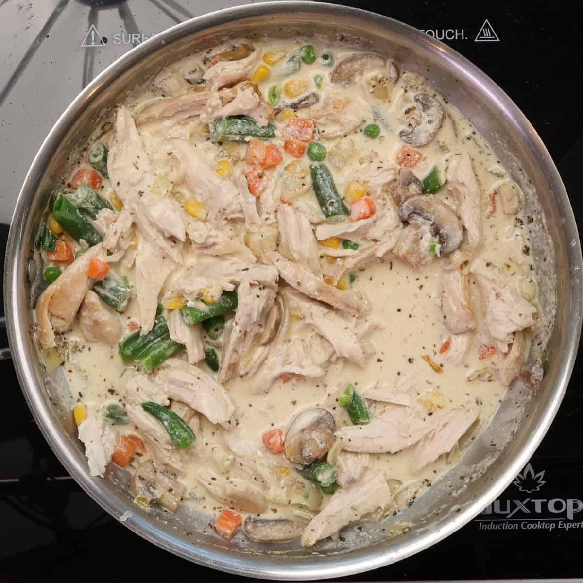 chicken with vegetables in a sauce in a skillet.