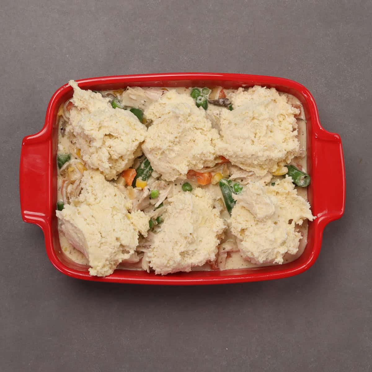 an unbaked chicken and biscuits casserole in a baking dish.