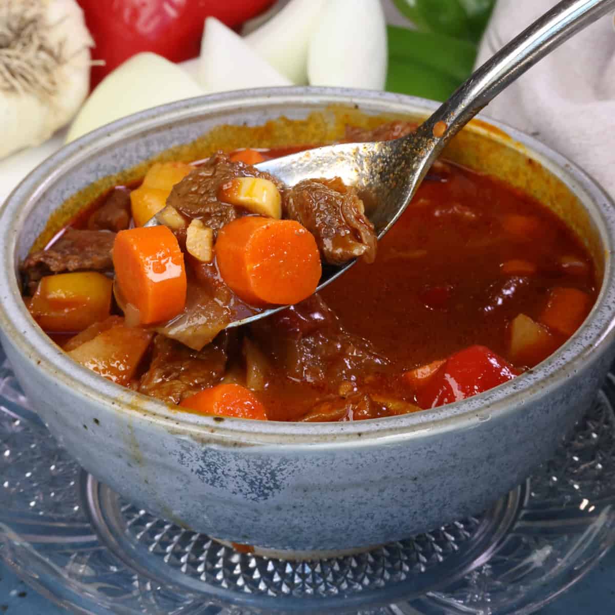 a bowl of hungarian goulash with a spoon on the side.