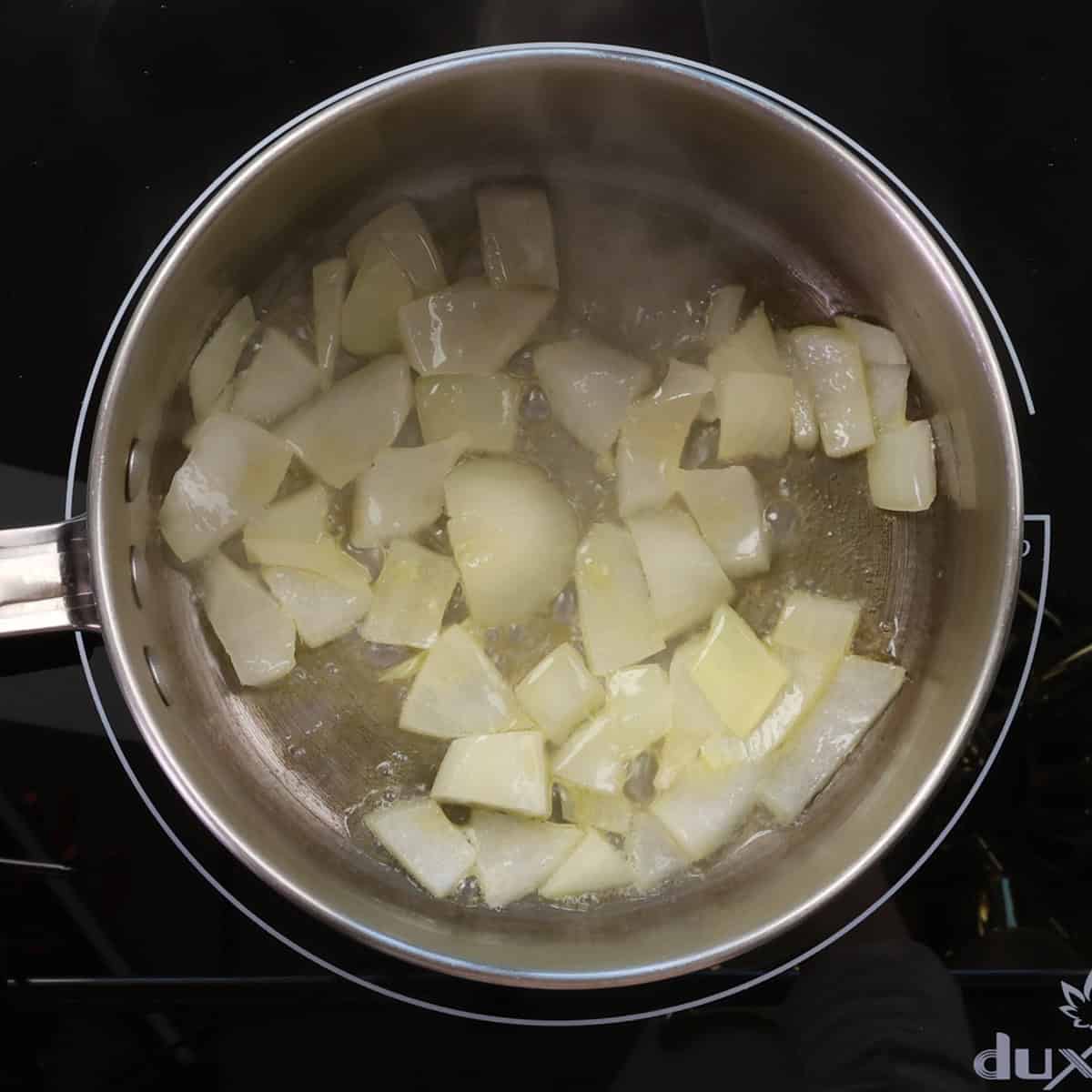 chopped onions cooking in butter in a small pot.