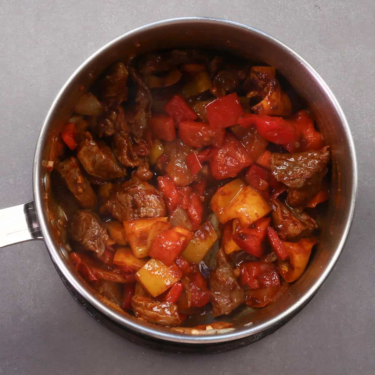 a pot filled with beef and vegetables tossed with paprika.