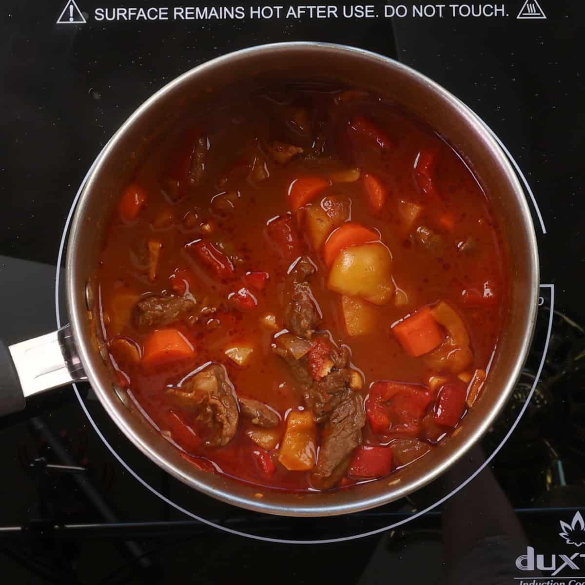 hungarian goulash with potatoes and vegetables simmering on the stove.