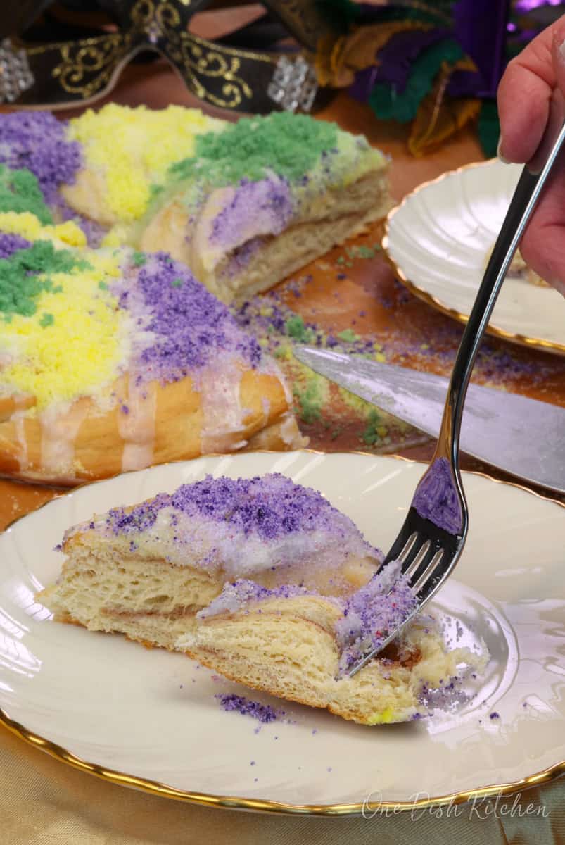 a slice of king cake on a white plate with a fork on the side.