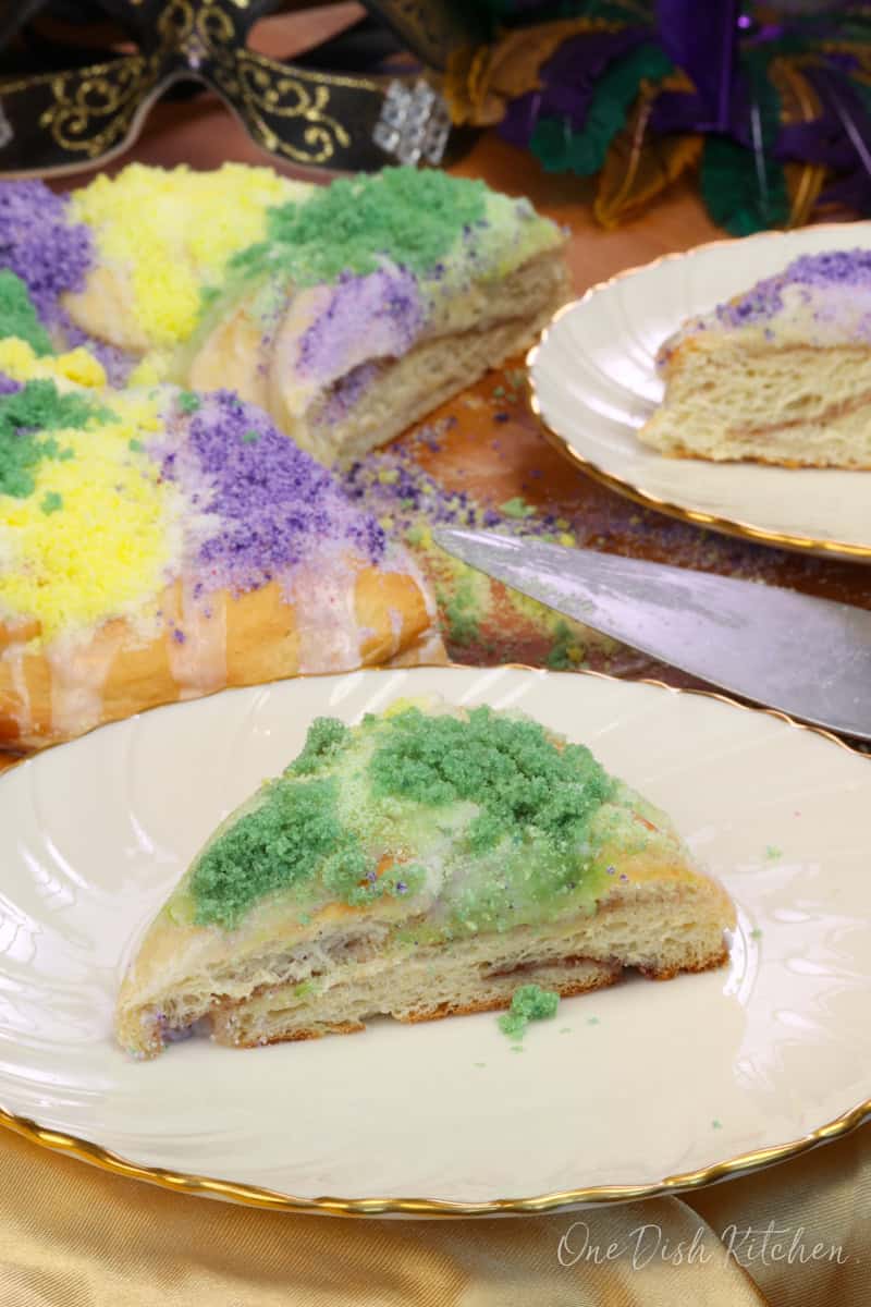 a slice of king cake topped with green sugar on a plate.