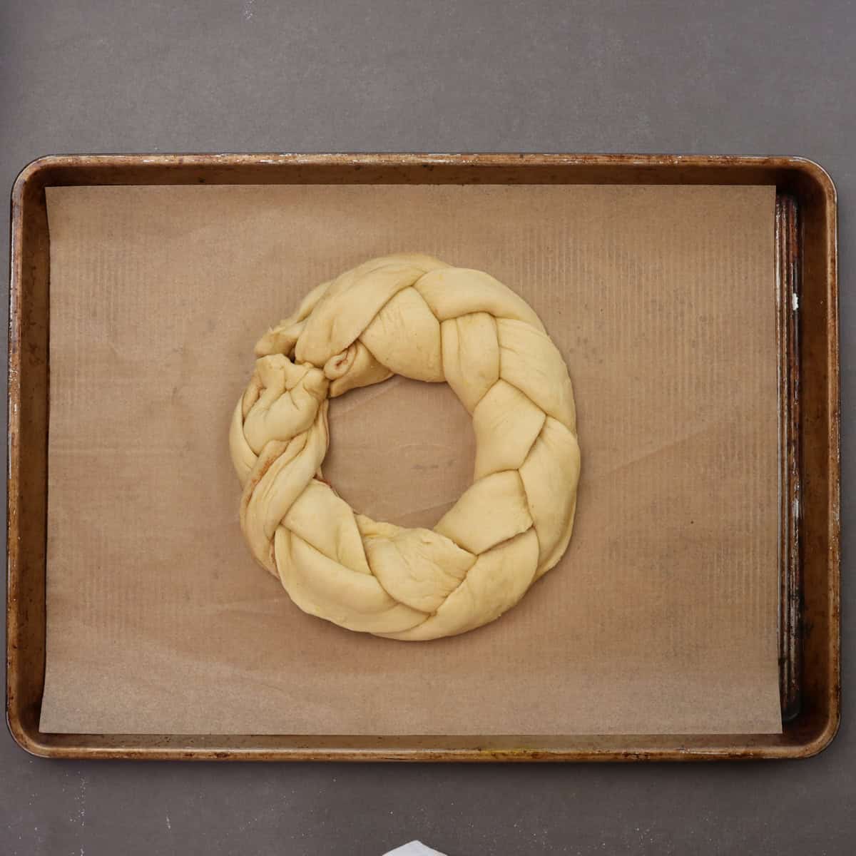 a braided king cake on a parchment lined baking sheet.