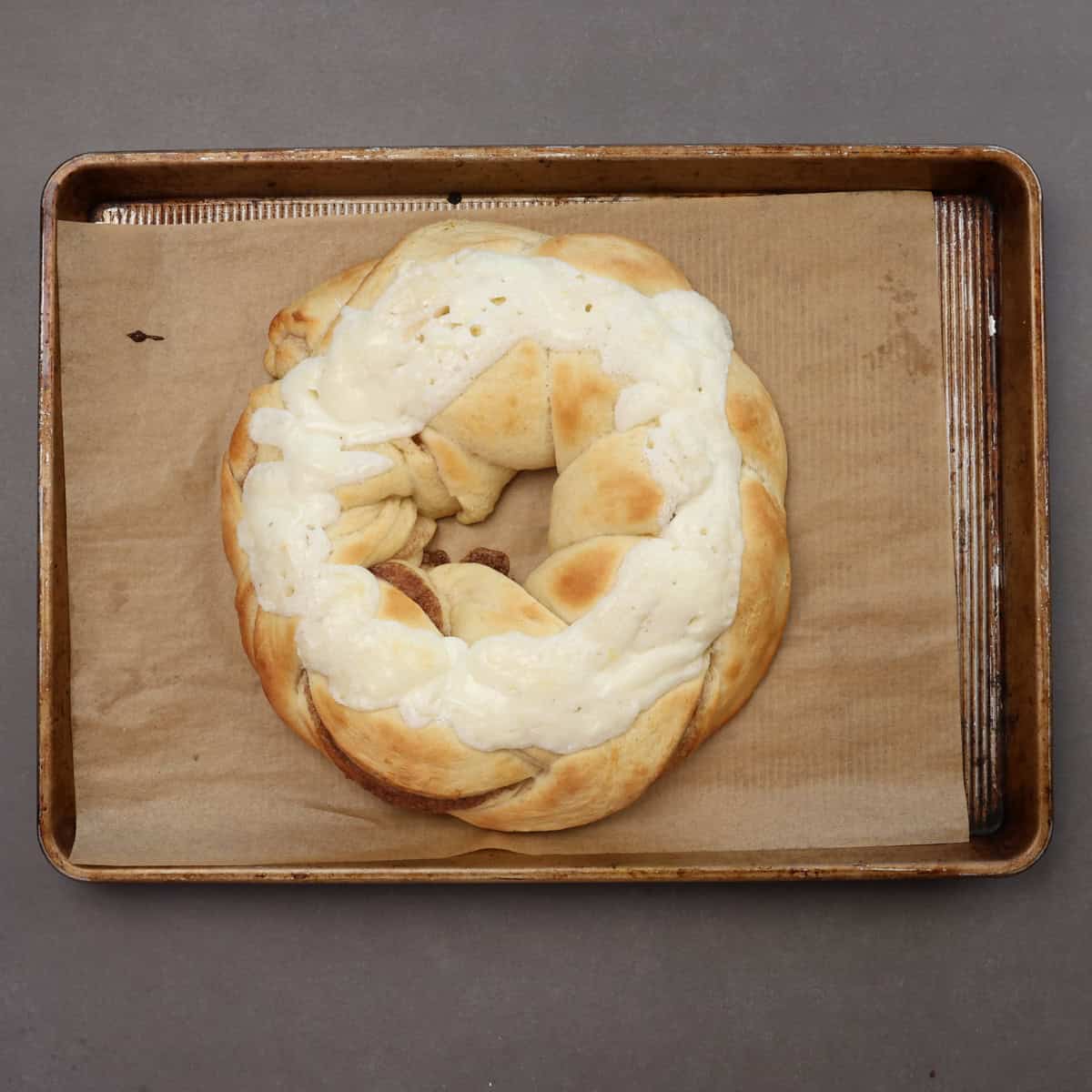 a baked king cake with cream cheese topping on a baking sheet.